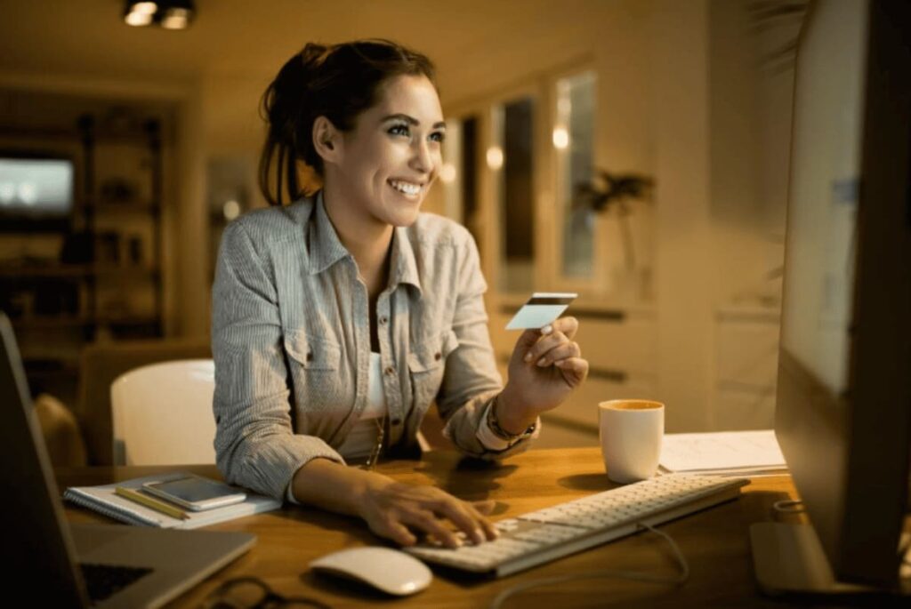 Foto de jovem em casa pedindo delivery de comida com seu cartão de benefício flexível