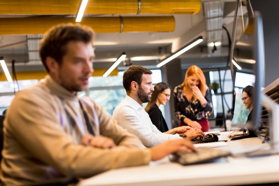 Equipe trabalhando em escrit&oacute;rio moderno, representando tipos de benef&iacute;cios corporativos e ambiente de trabalho.
